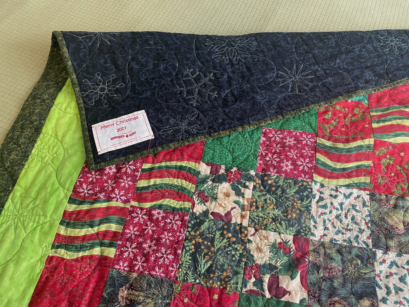 Image shows a quilted blanket with random patterns in holiday colors.
