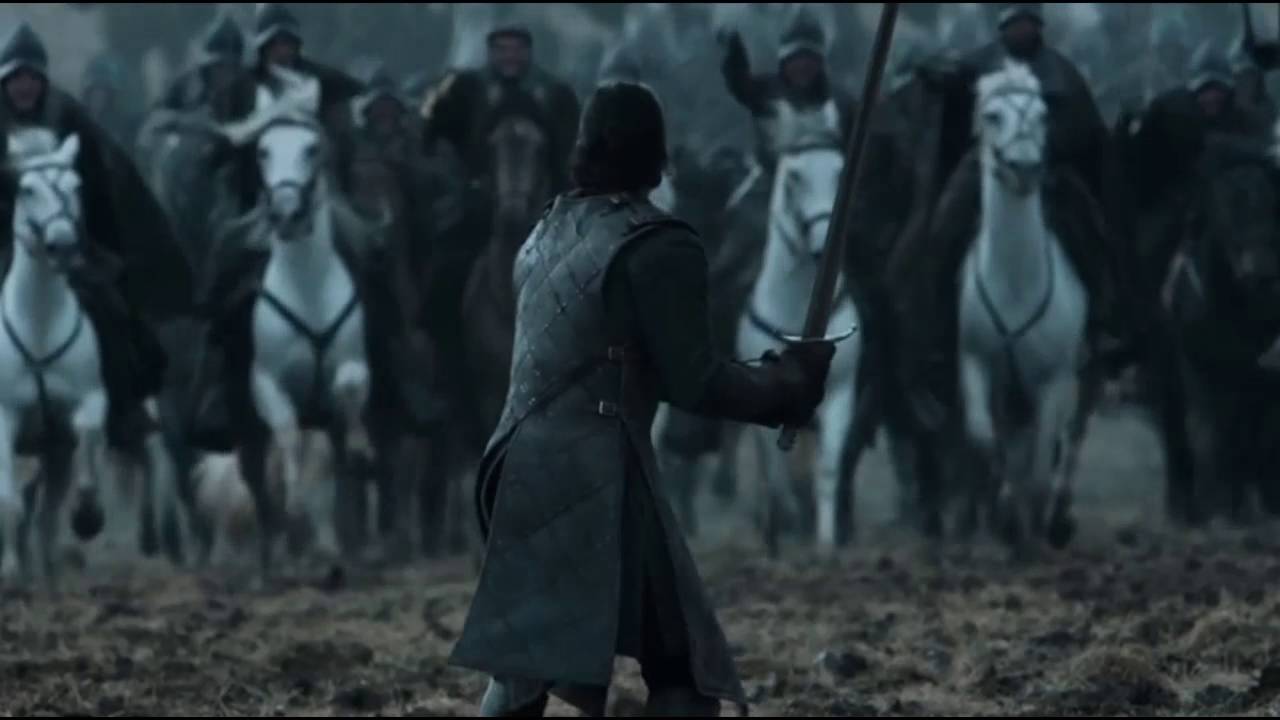 A warrior stands alone with his sword, facing an oncoming charge by soldiers on horseback.
