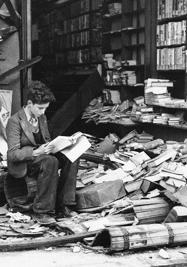 Boy reading in bombed bookstore. London, 1940.
